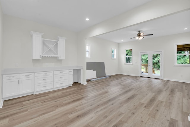 unfurnished living room with light hardwood / wood-style floors, ceiling fan, and french doors