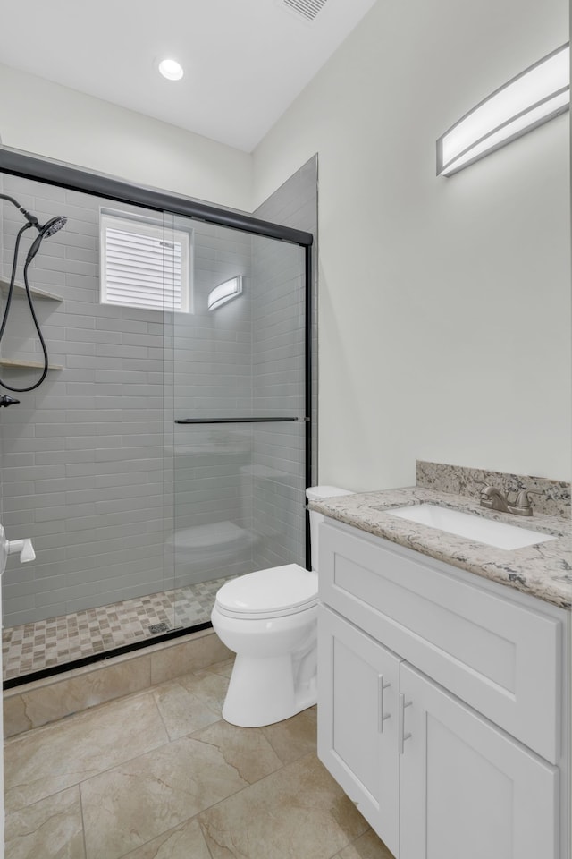 bathroom featuring vanity, toilet, and a shower with shower door