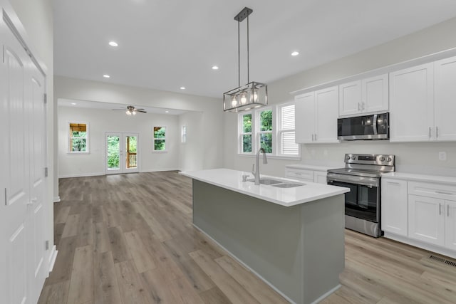 kitchen featuring stainless steel appliances, a wealth of natural light, white cabinets, and sink