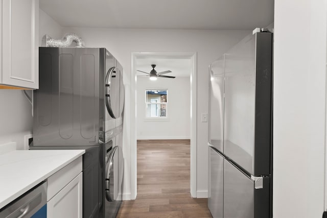 laundry area with ceiling fan, stacked washer and dryer, cabinets, and dark wood-type flooring