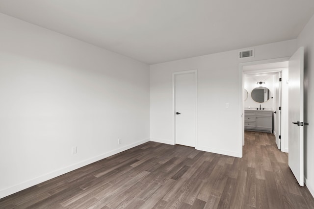 unfurnished bedroom featuring dark hardwood / wood-style floors, a closet, and sink