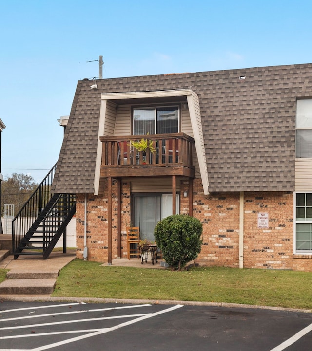 view of front of home featuring a balcony and a front lawn