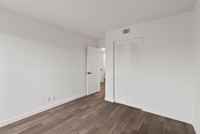 unfurnished bedroom with a closet and dark hardwood / wood-style floors