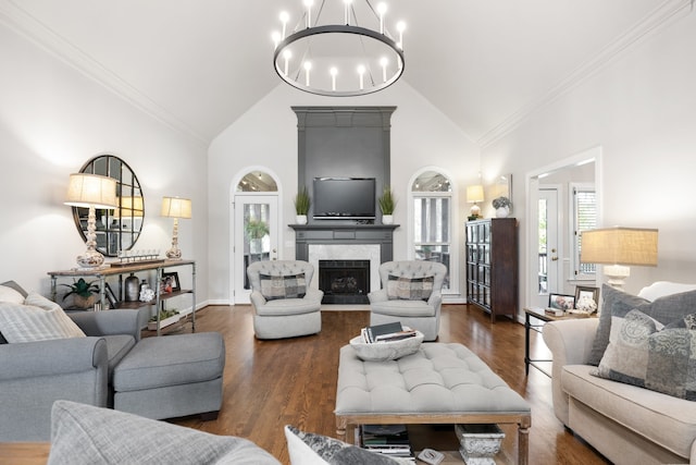 living room featuring ornamental molding, high vaulted ceiling, a fireplace, a notable chandelier, and dark wood-type flooring