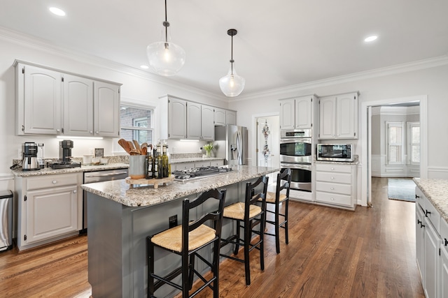 kitchen featuring crown molding, stainless steel appliances, decorative light fixtures, and a kitchen island