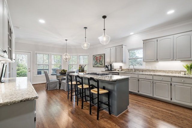 kitchen with dark hardwood / wood-style flooring, light stone countertops, a wealth of natural light, and a center island