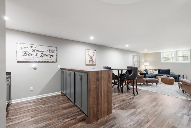 kitchen with dark wood-type flooring, kitchen peninsula, and dark brown cabinets