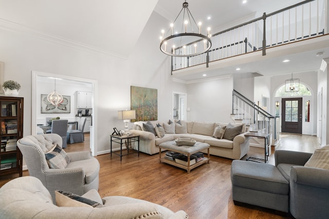 living room with hardwood / wood-style floors, a chandelier, high vaulted ceiling, and ornamental molding