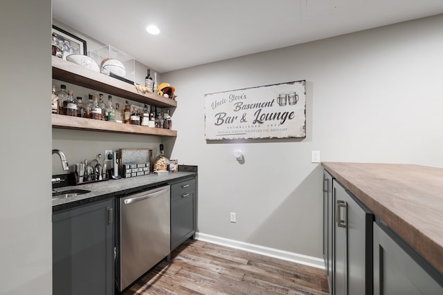 bar with stainless steel dishwasher, dark hardwood / wood-style floors, gray cabinetry, and sink