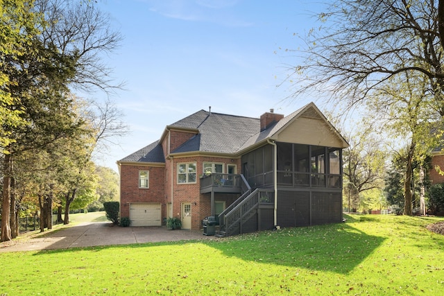 back of property featuring a garage, a lawn, and a sunroom