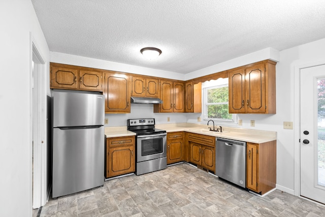 kitchen with a textured ceiling, sink, and stainless steel appliances