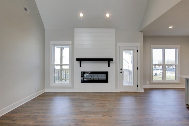 unfurnished living room featuring dark hardwood / wood-style floors, vaulted ceiling, and a large fireplace