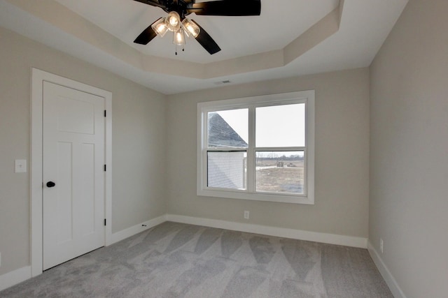 carpeted empty room featuring ceiling fan and a tray ceiling