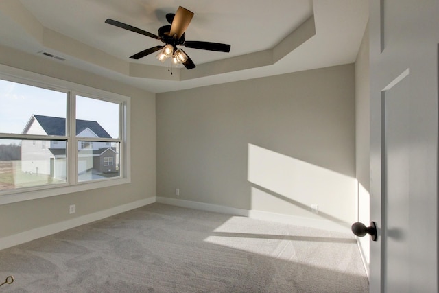 unfurnished room with light carpet, ceiling fan, and a tray ceiling