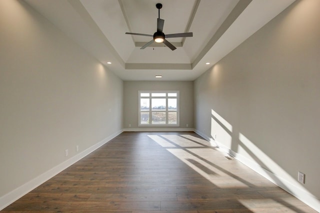 spare room featuring ceiling fan, dark hardwood / wood-style floors, and a raised ceiling