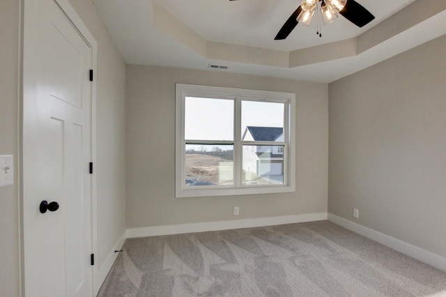 spare room with light carpet, ceiling fan, and a tray ceiling