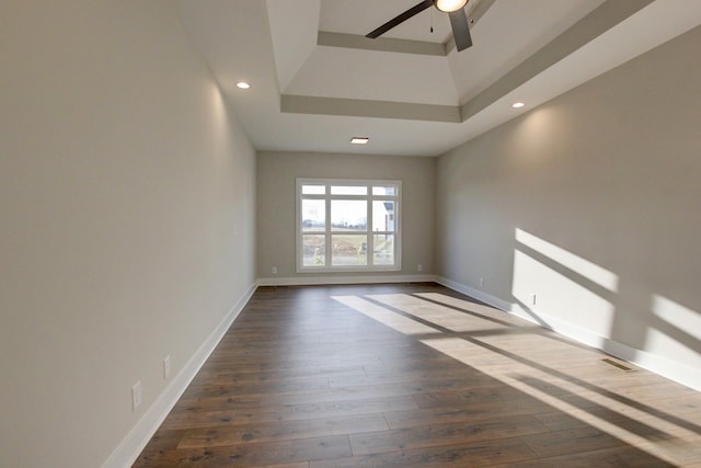 unfurnished room with ceiling fan, dark hardwood / wood-style flooring, a raised ceiling, and a high ceiling