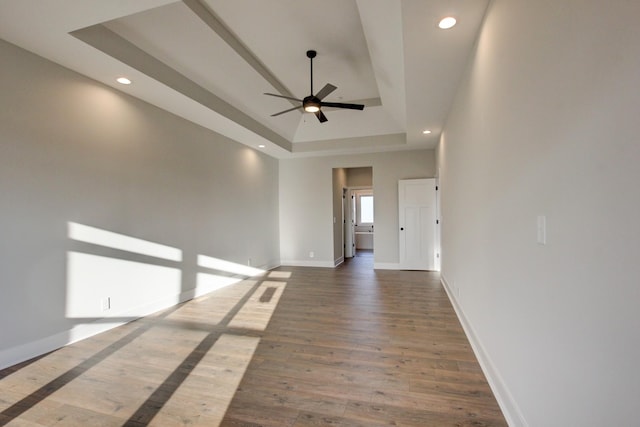 spare room featuring a raised ceiling, wood-type flooring, and ceiling fan