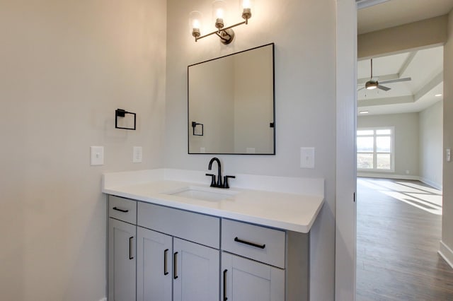 bathroom featuring hardwood / wood-style flooring, vanity, a raised ceiling, and ceiling fan