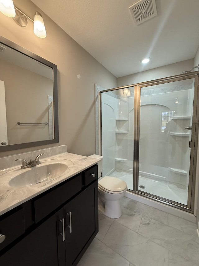 bathroom featuring vanity, toilet, and a shower with shower door