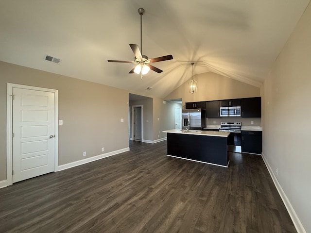 kitchen featuring ceiling fan, stainless steel appliances, a center island with sink, dark hardwood / wood-style flooring, and vaulted ceiling