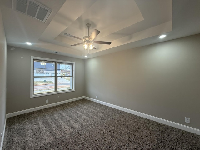 unfurnished room featuring a raised ceiling, carpet, and ceiling fan