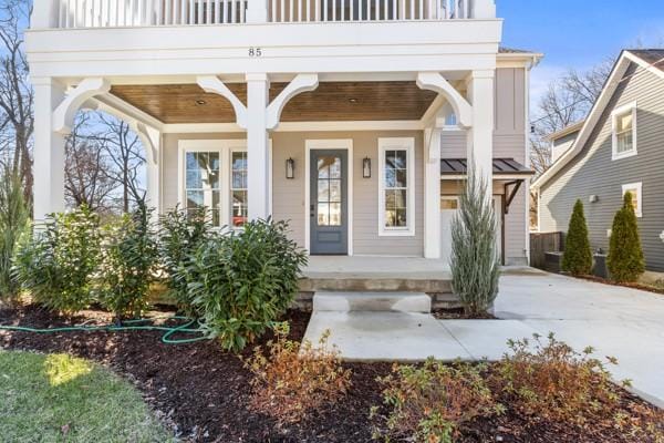 entrance to property featuring driveway, a porch, and a balcony