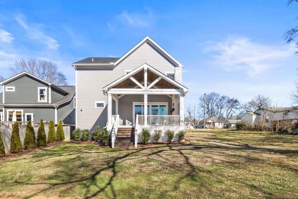 view of front of home with a porch, a front yard, and fence