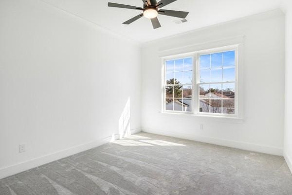 carpeted empty room with ornamental molding, visible vents, ceiling fan, and baseboards