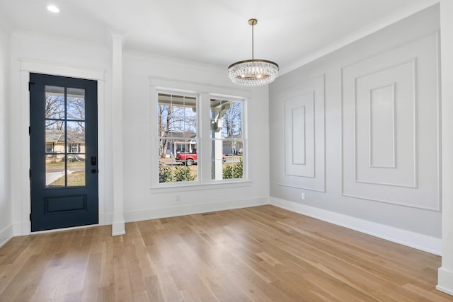 interior space with an inviting chandelier, crown molding, baseboards, and light wood-style floors