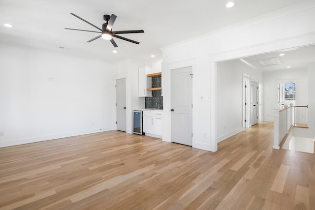 unfurnished living room featuring light wood finished floors, wine cooler, and recessed lighting