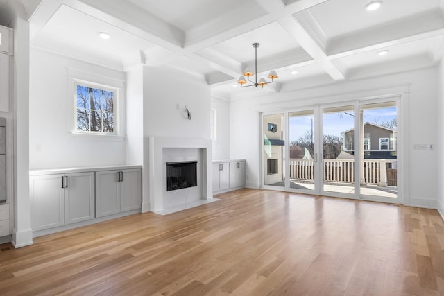 unfurnished living room with a chandelier, coffered ceiling, a fireplace with flush hearth, light wood-type flooring, and beam ceiling