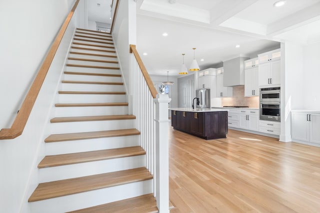 stairway featuring wood finished floors and recessed lighting