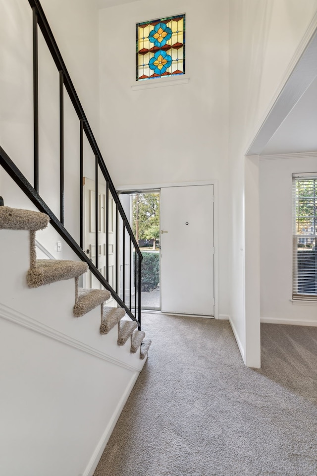 carpeted foyer entrance featuring a towering ceiling