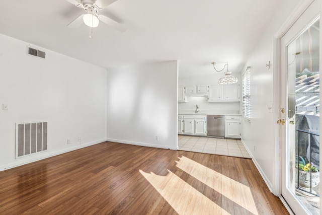 unfurnished living room featuring ceiling fan with notable chandelier, sink, and light hardwood / wood-style flooring