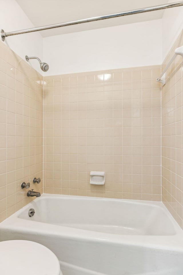 bathroom with toilet and tiled shower / bath combo