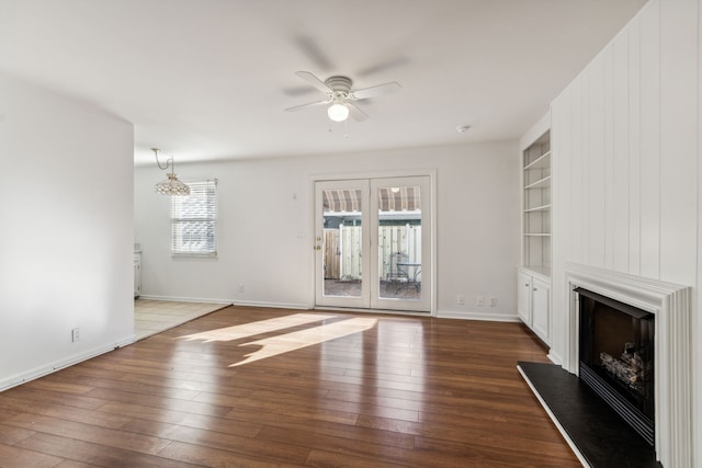 unfurnished living room featuring built in shelves, plenty of natural light, and wood-type flooring