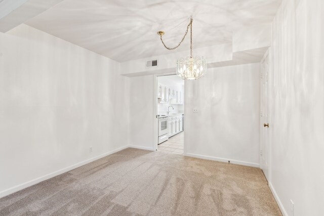 unfurnished room with sink, light colored carpet, and a notable chandelier