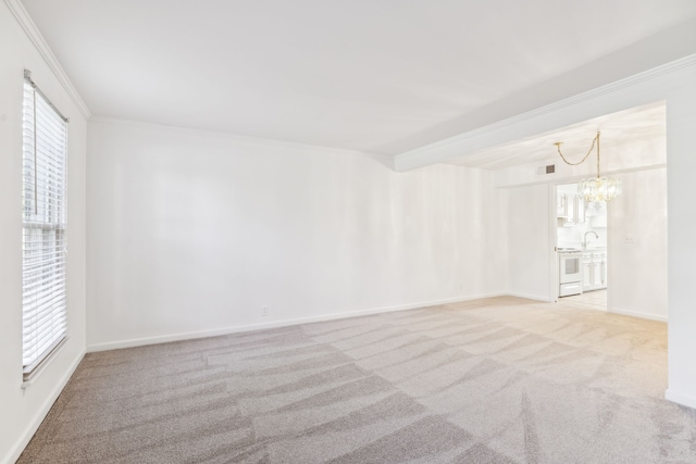 empty room with a chandelier, a wealth of natural light, light carpet, and crown molding