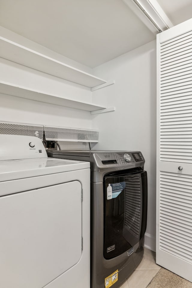 laundry room featuring washing machine and clothes dryer and light tile patterned flooring