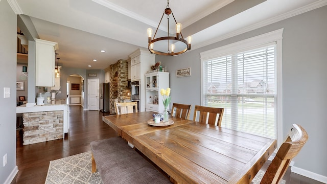 dining room with dark wood-type flooring, sink, an inviting chandelier, ornamental molding, and a raised ceiling