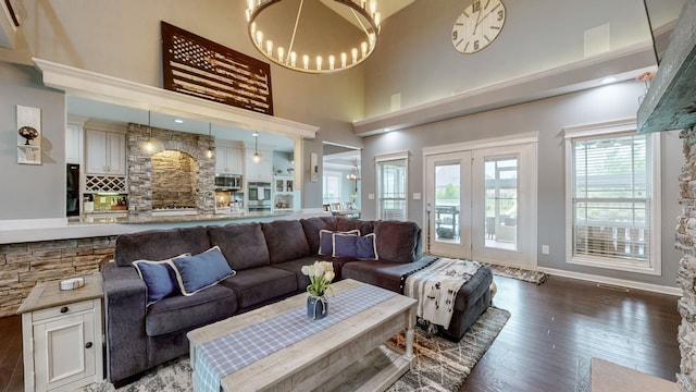 living room with a notable chandelier, dark wood-type flooring, and a high ceiling