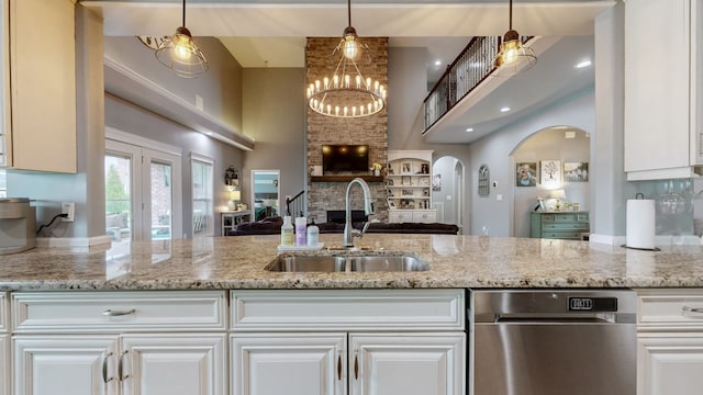 kitchen with light stone counters, sink, and decorative light fixtures