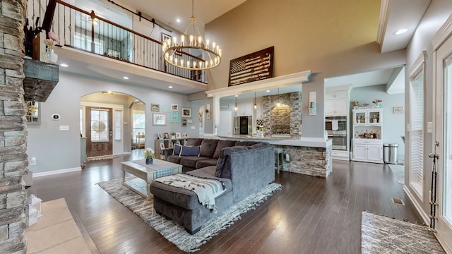 living room with a high ceiling, dark hardwood / wood-style floors, and an inviting chandelier