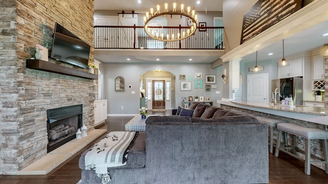 living room with an inviting chandelier, a fireplace, dark hardwood / wood-style flooring, and a high ceiling