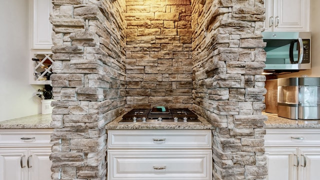 kitchen featuring light stone countertops, white cabinetry, and appliances with stainless steel finishes