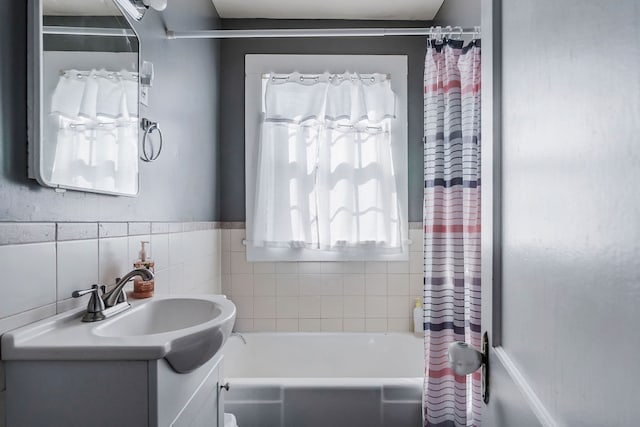 bathroom with tile walls, vanity, and shower / bathtub combination with curtain