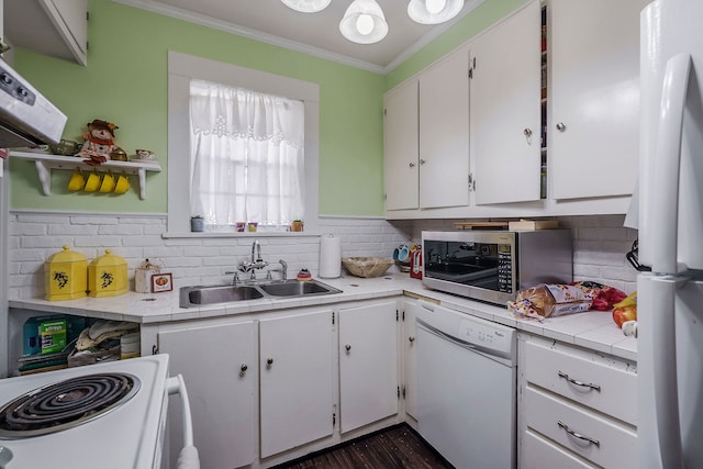 kitchen with tile counters, sink, ornamental molding, white cabinetry, and white appliances