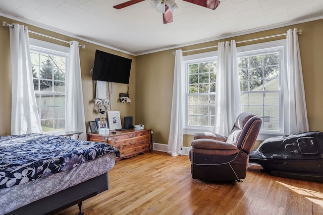 bedroom with hardwood / wood-style floors, ceiling fan, and crown molding