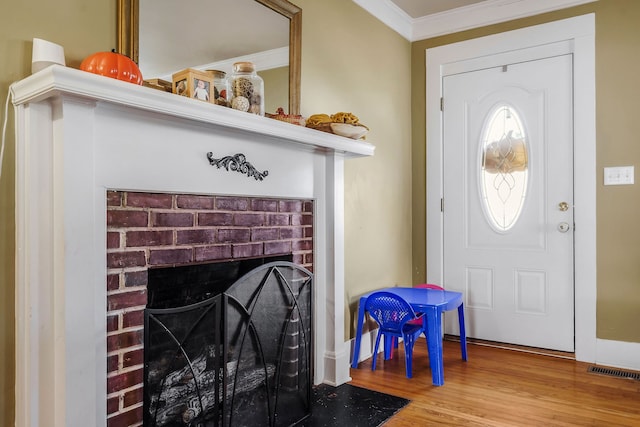 entryway with a fireplace, light hardwood / wood-style flooring, and ornamental molding